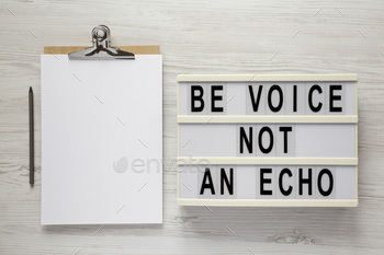 'Be voice not an echo' on a lightbox, clipboard with blank sheet of paper