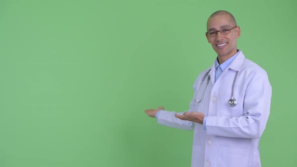Happy Bald Multi Ethnic Man Doctor Showing To Back and Giving Thumbs Up