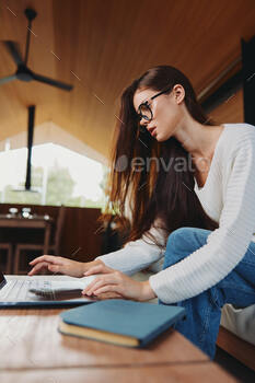 Smiling Woman Using Laptop on Sofa at Home, a Millennial Teacher in Glasses Relaxing in her Cozy