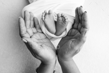 The palms of the father, the mother are holding the foot of the newborn baby.