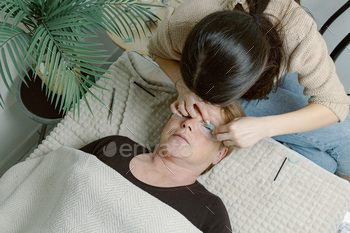 A girl cosmetologist laminates women's eyelashes.