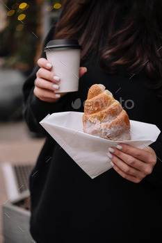 Woman holding fresh pastry and coffee outdoors