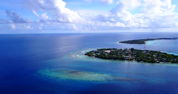 Wide above island view of a white paradise beach and blue water background in vibrant 