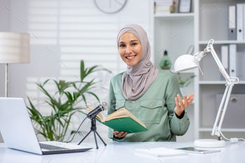 Confident woman in hijab hosting a podcast at home desk with book and microphone