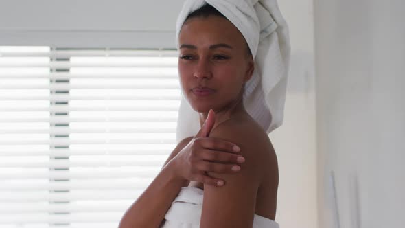 Portrait of african american woman touching her skin in the bathroom