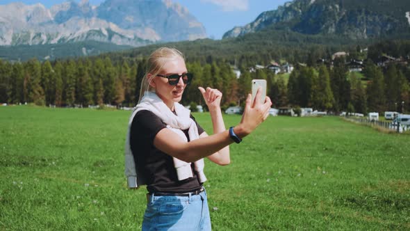 Woman Making Video Call From Beautiful Nature Park in Front of Mountains