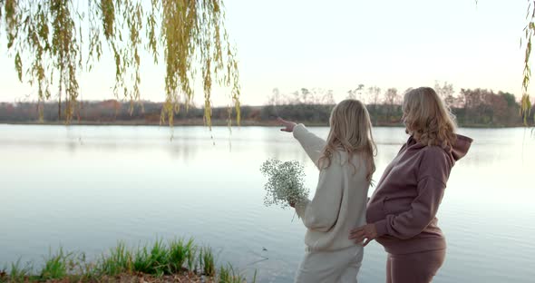 Pregnant Mother with Blonde Adult Daughter in Beige Clothes in Autumn Evening Park