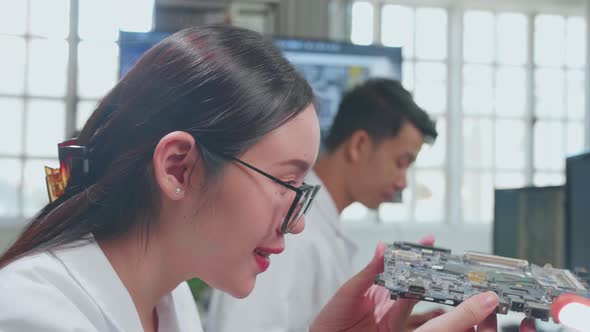 Asian Female Engineer Inspects Printed Circuit Board Motherboard. Scientist Designs Industrial Pcb