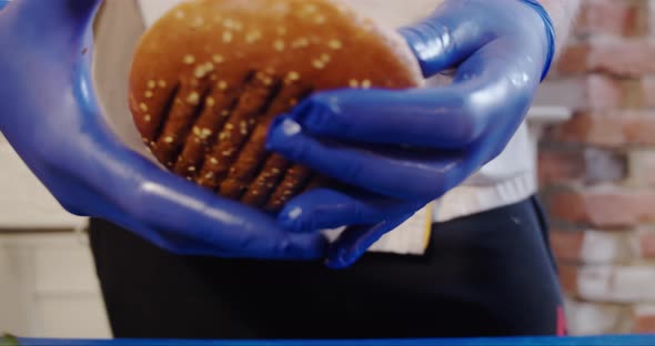 Close Up. The Cook Hands Placing Top Bun on a Burger. . Slow Motion