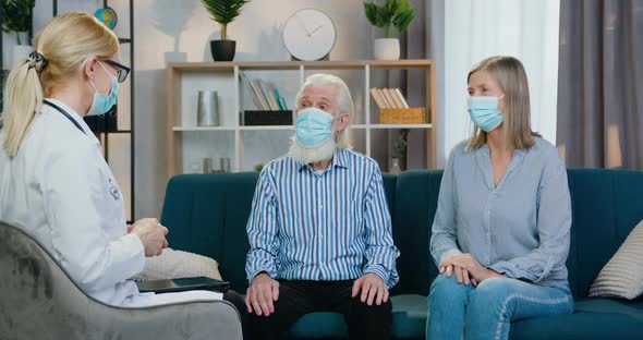 Doctor in Mask Listening Senior Couple which Wear Protective Masks During Home visit