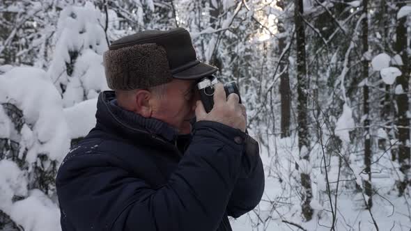 Old Man Is Taking Photo of Snowy Forest at Winter Day Photographing Nature By Camera Standing Alone