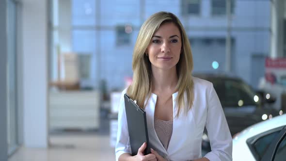 Young Confident Woman with Document Folder Walking in Car Dealership Leaving