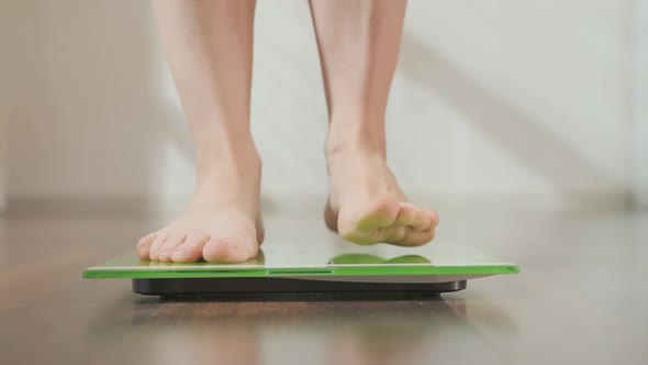 Woman checking body weight. Female feet on floor measuring scales