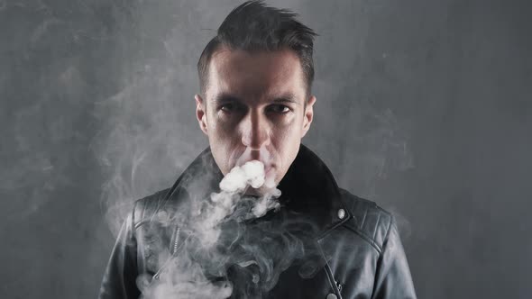 Portrait of Brutal Smoker Man in Leather Jacket Looking at Camera