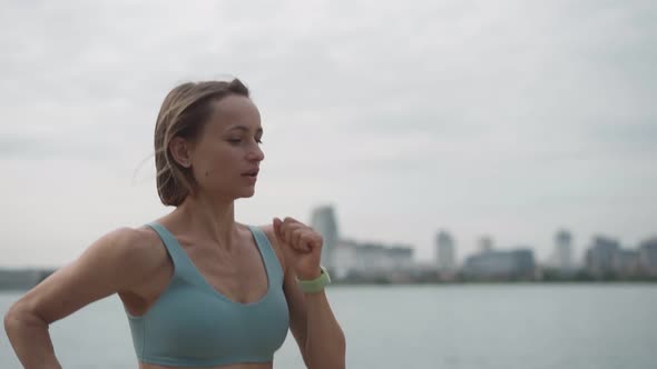 Slow Motion Young Sportswoman in Sportswear Trains in a Park Near the River