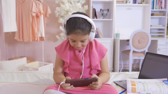 Little girl playing on the phone in her room.