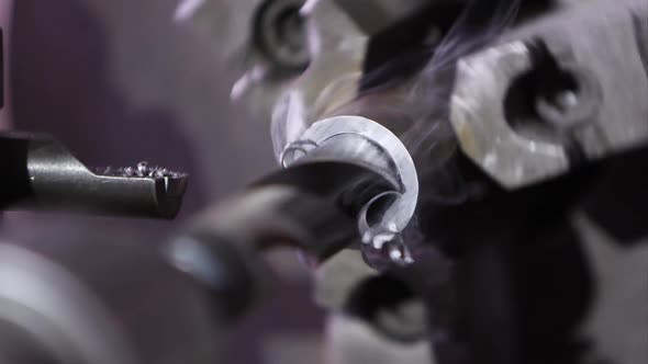 Metal lathe drilling into steel rod as metal curls out from the bit