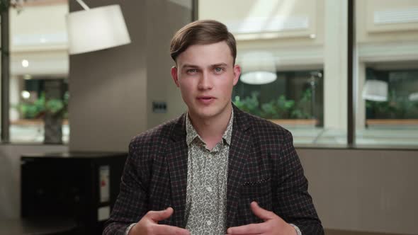 A male office worker communicates on zoom with colleagues at work (look at the camera)