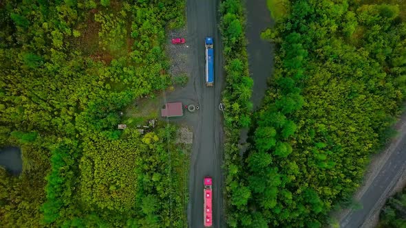 Red And Blue Transport Trucks Moving Valuable Minerals Through Forest Area