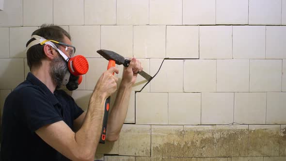Bearded Middleaged Worker in Respirator and Protective Glasses with Tools is Trying to Tear Off an