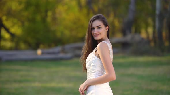 Beautiful Brunette Bride with Deep Look Is Looking Right and Begins To Smiling in Sunny Rays at the