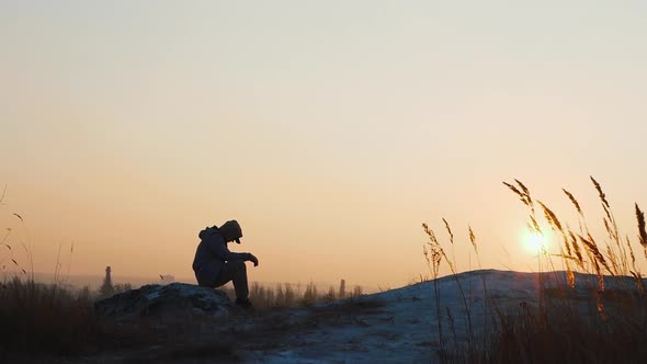 Young Man On A High Mountain Against The Backdrop Of A Beautiful Sunset. Pensive Man On The Mountain