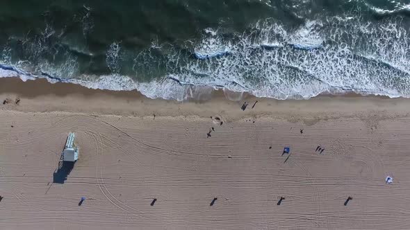 Birds eye view of waves on beach moving higher and upwards away from the beach revealing more of the