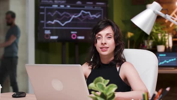 Young Businesswoman Sitting at the Desk, Lookint at Camera