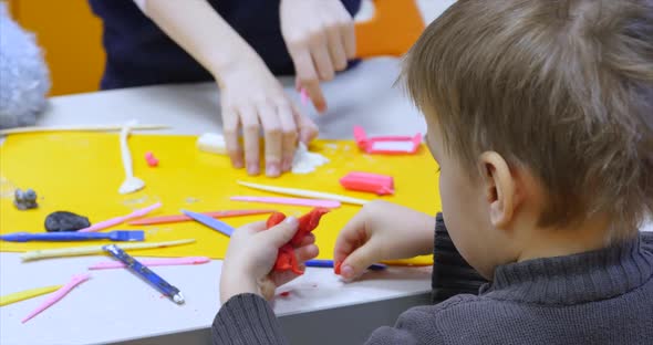 Young Male Child or Boy Artist in an Art Workshop, Sits at a Table and Sculpts From on Plasticine