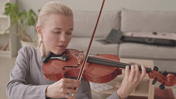 Concentrated Woman Playing Violin at Home