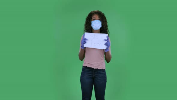 Portrait of Beautiful African American Young Woman in Medical Mask Is Looking at Camera and Holding