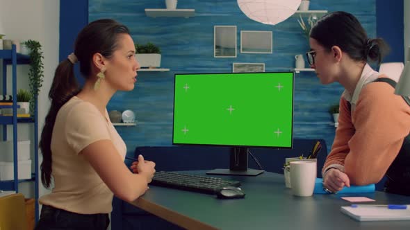 Two Collegues Working Together on Computer with Mock Up Green Screen Chroma Key Display