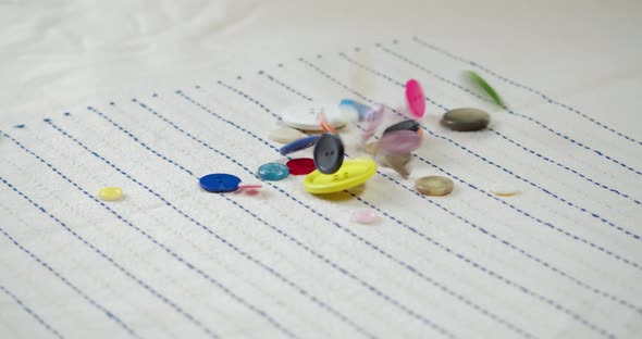 Colorful Buttons Falling on Striped Fabric Closeup