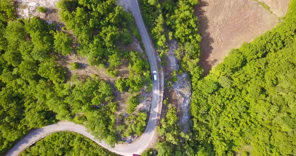 Aerial drone view of a minivan car vehicle driving on a rural road.