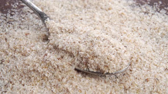 Full metal spoon of psyllium husk close up on wooden table. Macro