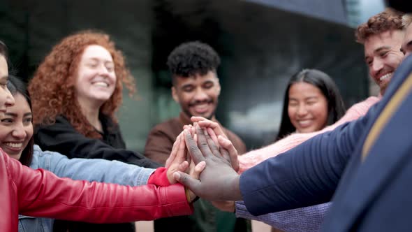 Multiracial group of people celebrating together stacking hands outdoor