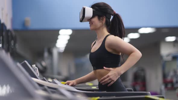 Happy Smiling Slim Sportswoman Running on Treadmill in VR Headset