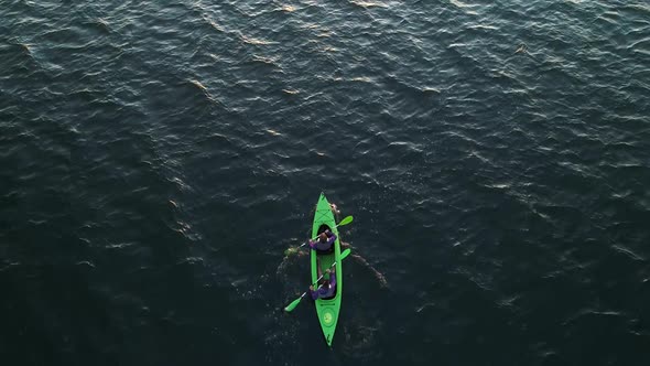 Young Man and Woman in a Green Kayak Paddle