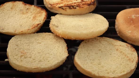 Female Hand Is Rotating Burger Buns with Kitchen Tongs