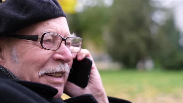 Older Man Talking on the Mobile Phone While Sitting in the Park