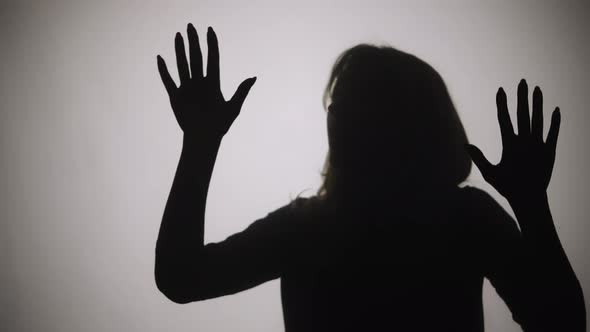 Silhouette of Woman Emerges From Smoke and Touches Glass with Her Palms