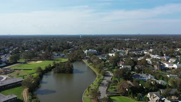 An aerial drone shot over a green pond in a suburban neighborhood on Long Island, NY.  The camera do