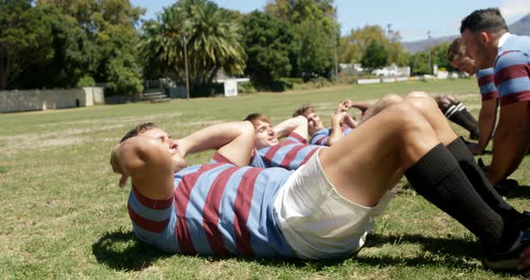 Rugby players doing crunches in the field 