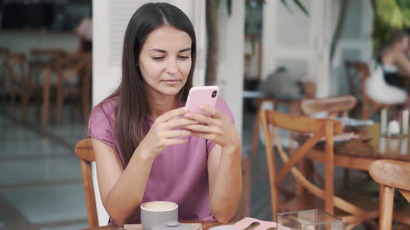 Portrait of Beautiful Girl Sitting in Cafe and Using Mobile Phone, Sends Message