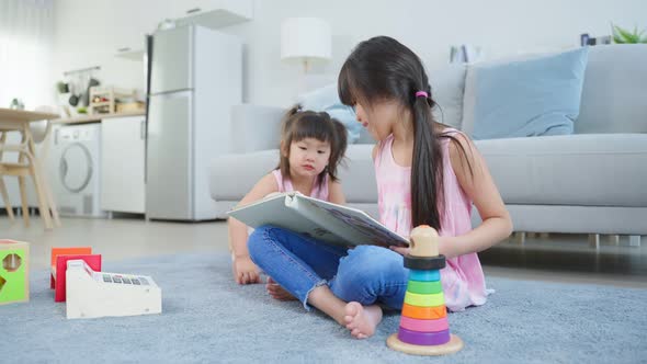 Asian big sister showing old album recalls the past to younger sibling. alt