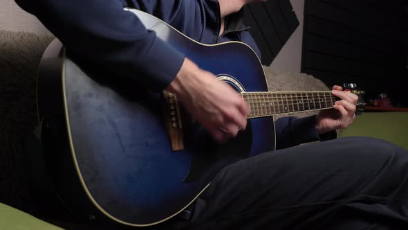 Man Plays a Pick on a Modern Guitar in the Dark