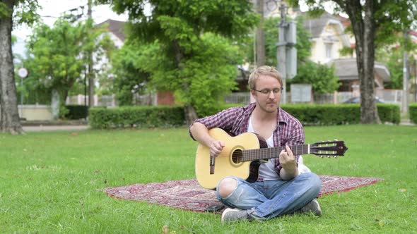 Portrait of Man Having Picnic While Playing the Guitar Outdoors