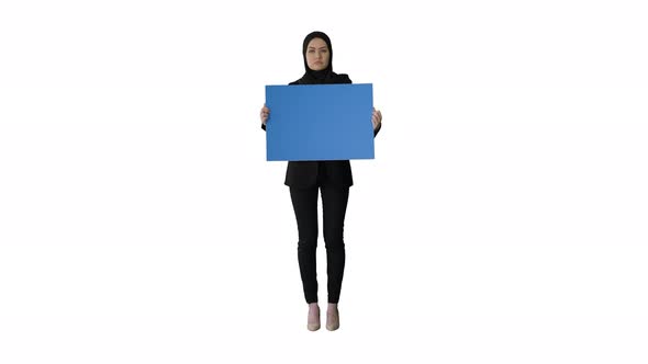 Serious Arab Woman in Hijab Holding Blank Blue Poster and Looking at Camera on White Background