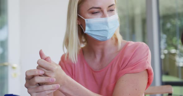 Mother and daughter wearing face masks sanitizing their hands at home