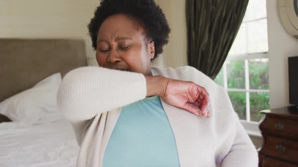 African american senior woman sneezing on her elbow